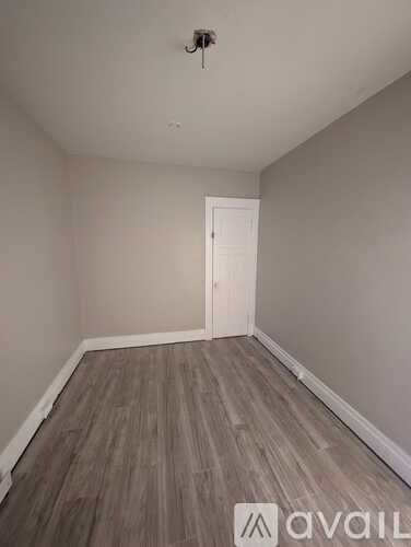 A room with wooden flooring and a white door.
