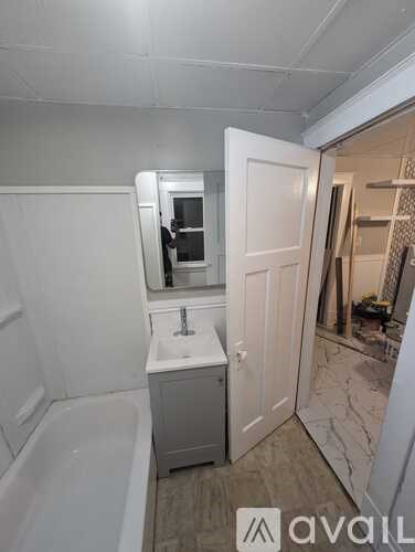 A bathroom with a white tub and sink, and a white door.