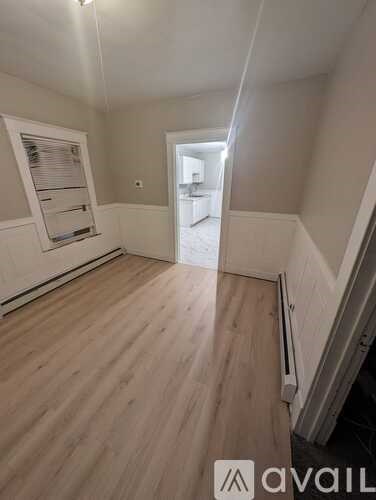 A room with wooden flooring and a window with blinds.