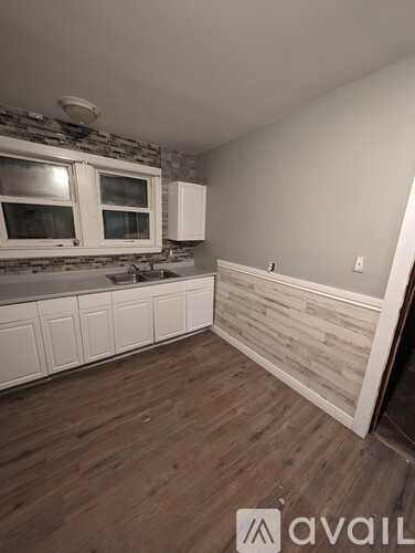 A kitchen with white cabinets and a stone backsplash.