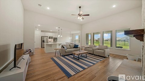 A spacious living room with a large rug and a ceiling fan.