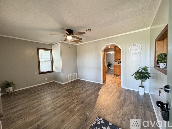 A living room with wood flooring and a ceiling fan.