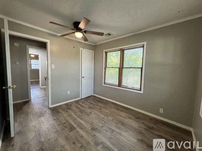A room with a ceiling fan and a window with a view of trees.