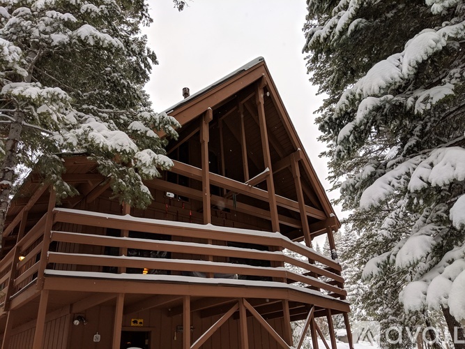 A wooden cabin in the woods covered in snow.