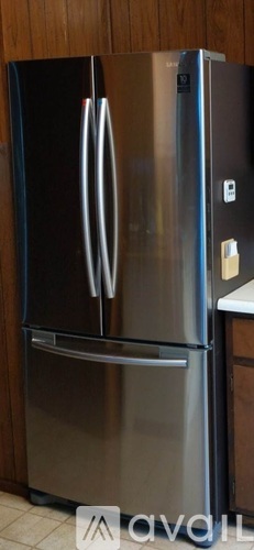 A stainless steel refrigerator with two doors is in a kitchen.