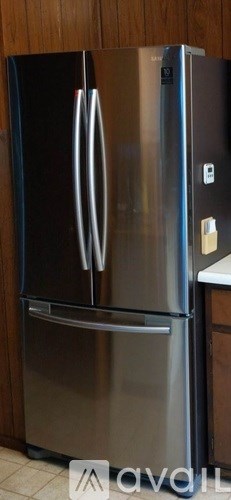 A stainless steel refrigerator with two doors is in a kitchen.