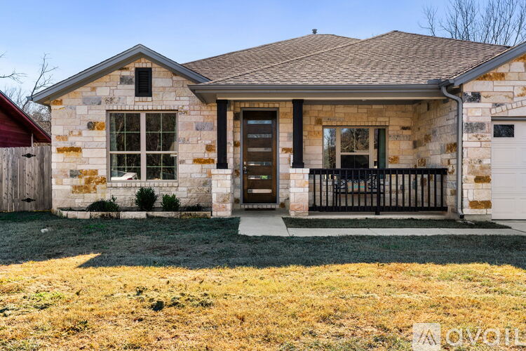 A house with a brown door and windows is surrounded by a grassy area with yellow flowers.