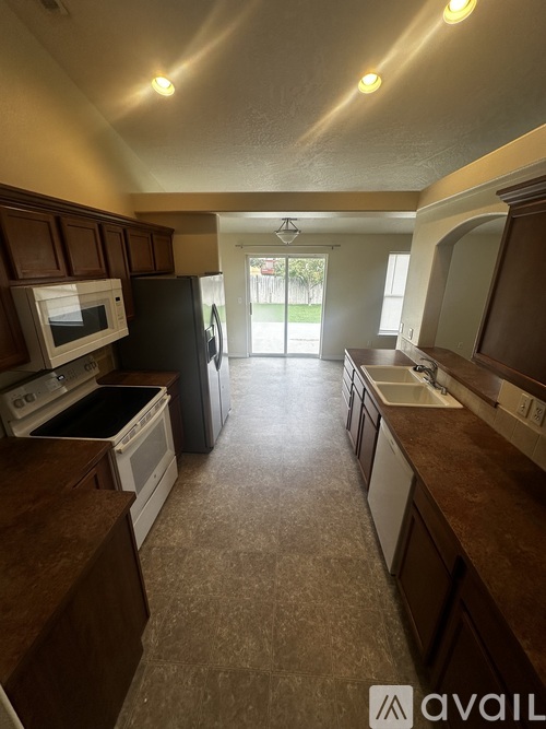 A kitchen with brown cabinets and a black refrigerator.