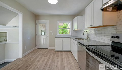 A kitchen with white cabinets and a wooden floor.