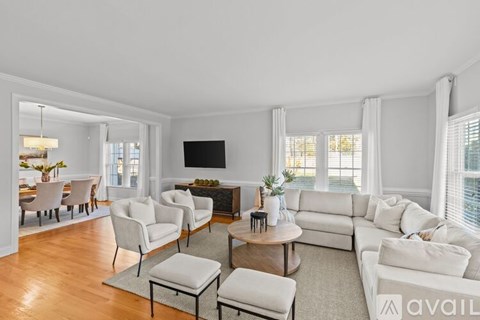 A living room with white furniture and a flat screen TV.