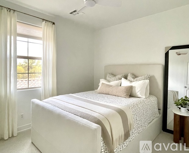 A bedroom with a large bed and a window with curtains.