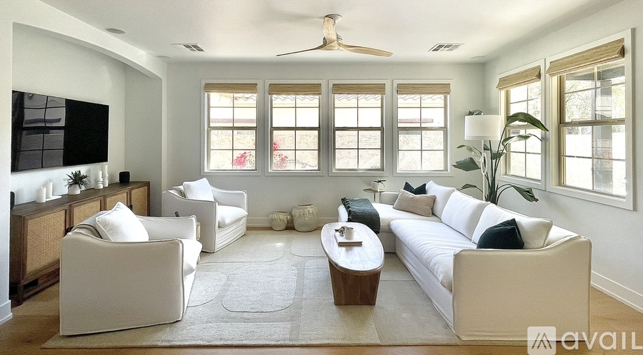A living room with a white couch, a white chair, and a white rug.