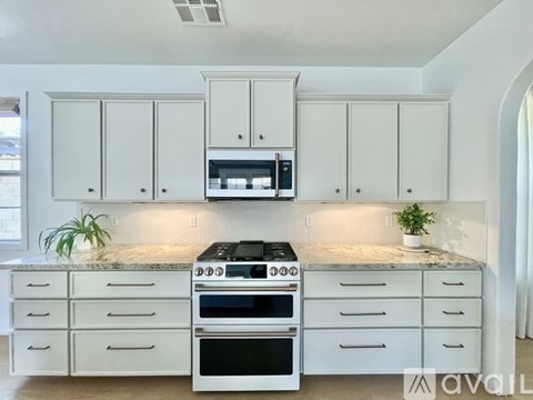 A kitchen with white cabinets and a black stove top oven.
