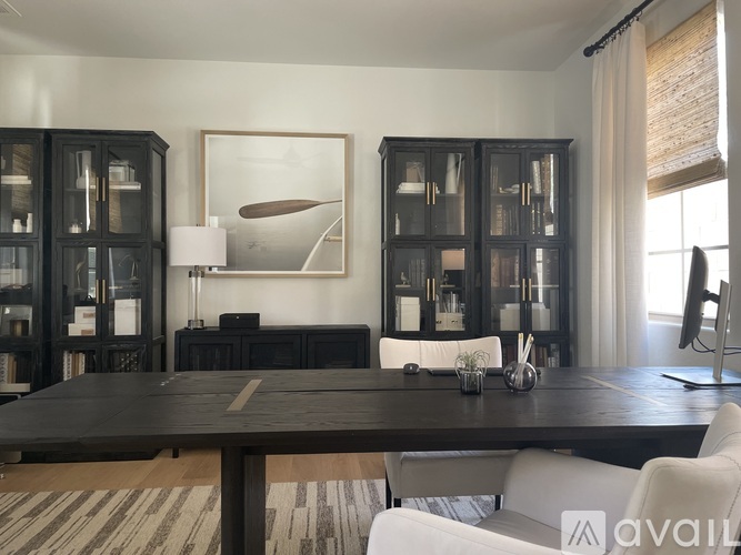 A modern dining room with a dark wood table and white chairs.