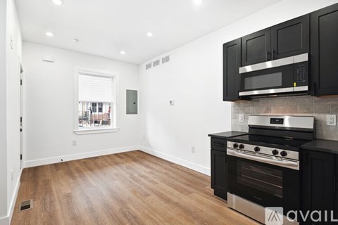A kitchen with black cabinets and a stainless steel oven.