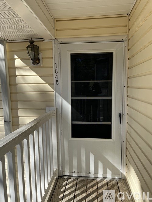 A white door with a glass window is on the porch.