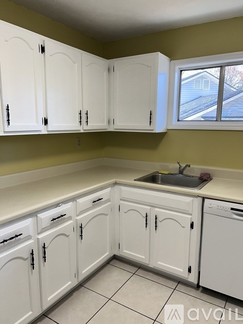 A kitchen with white cabinets and a window.