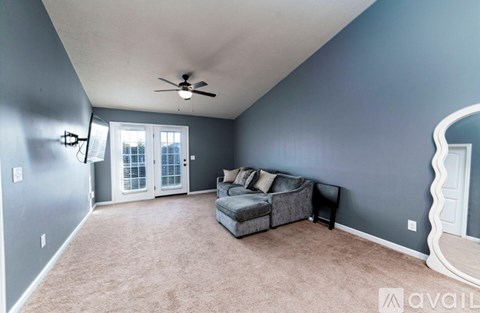 A living room with a grey couch and a ceiling fan.