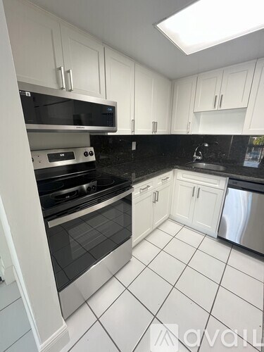 A kitchen with white cabinets and black countertops.