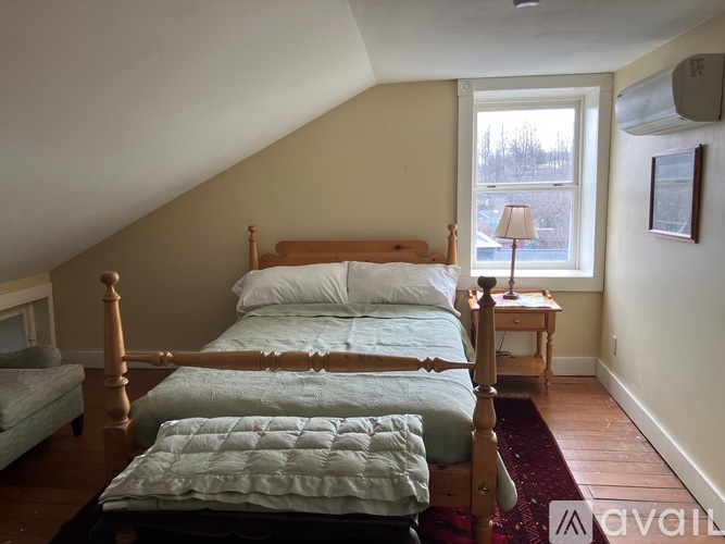A bedroom with a large bed and a small table by the window.