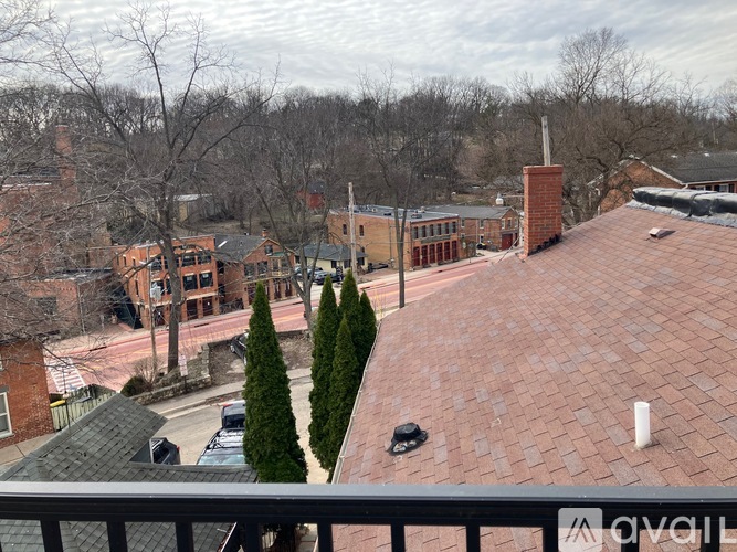 A view from a balcony overlooking a red brick building and a parking lot.