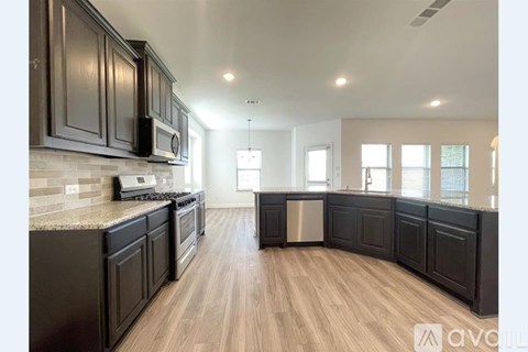 A kitchen with dark wood cabinets and a granite countertop.