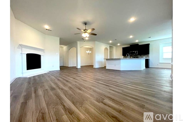 A spacious room with wooden flooring and a ceiling fan.