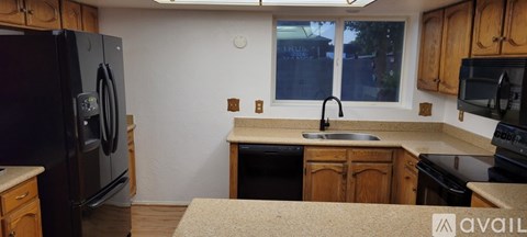 A kitchen with a black refrigerator and wooden cabinets.