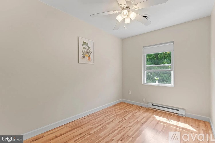A room with a ceiling fan and a window showing greenery outside.