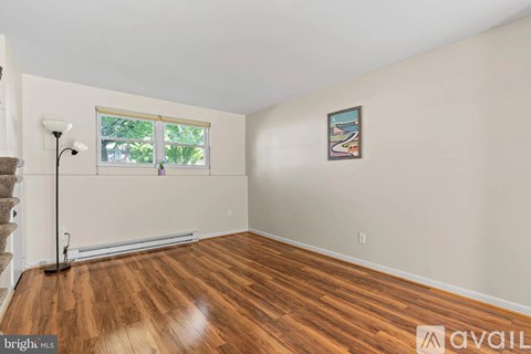 A room with wooden flooring and a window with a view of trees outside.