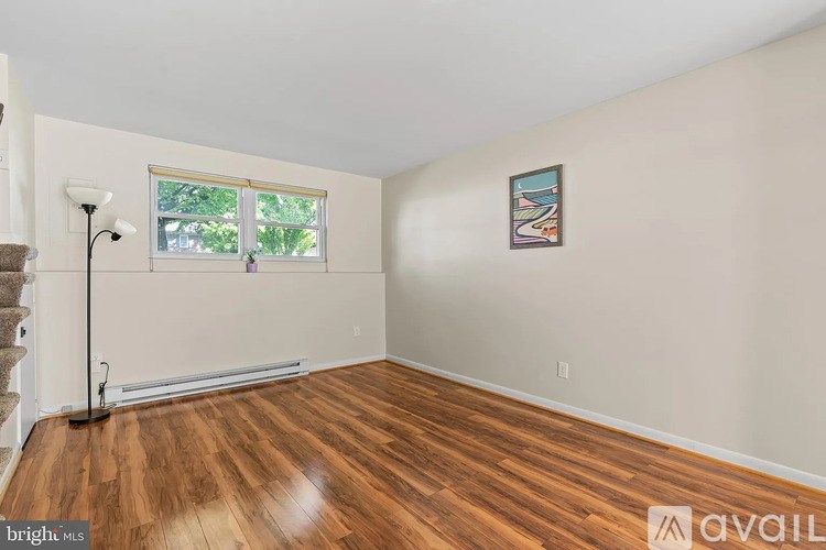 A room with wooden flooring and a window with a view of trees outside.