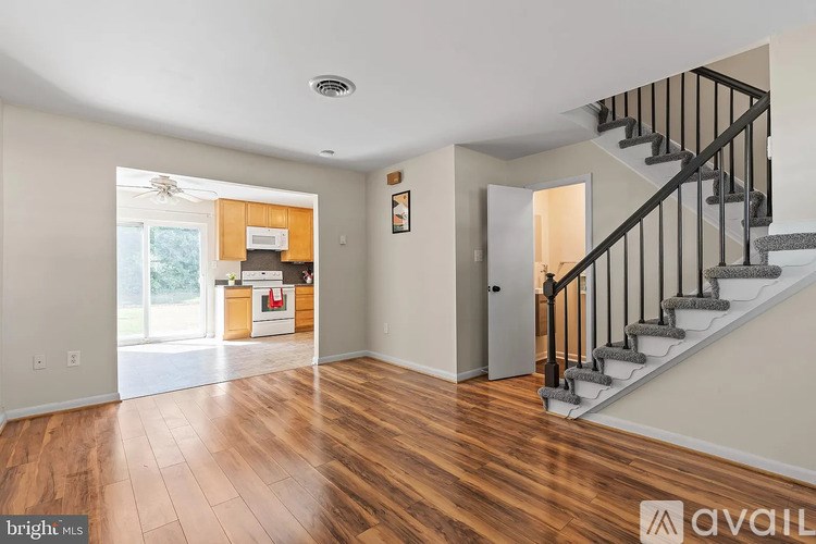 A spacious room with wooden floors and a staircase leading to another room.