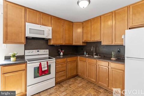 A kitchen with wooden cabinets and a white stove top oven.