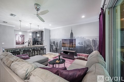 A living room with a couch, a table, and a fan.