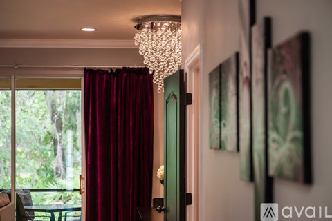 A room with a chandelier, a green door, and a painting on the wall.