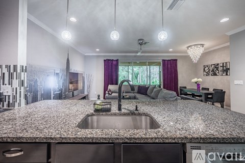 A modern kitchen with a granite countertop and a stainless steel sink.