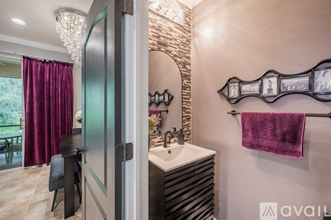 A bathroom with a sink, mirror, and a purple towel.