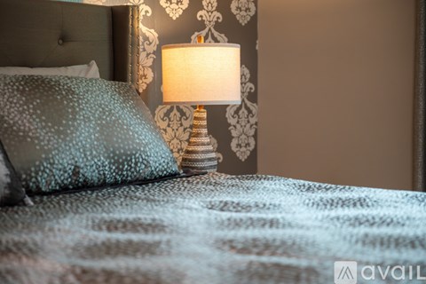 A bed with a blue comforter and a lamp on a side table.