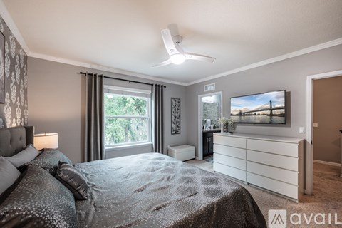A bedroom with a large bed and a television on the wall.