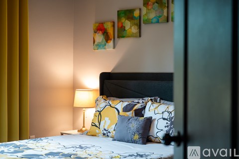 A bedroom with a bed, lamp, and two paintings on the wall.