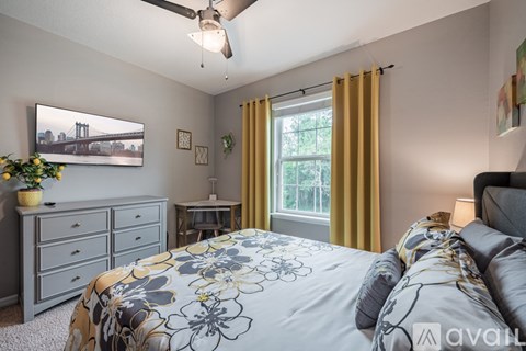 A bedroom with a bed, dresser, and a ceiling fan.