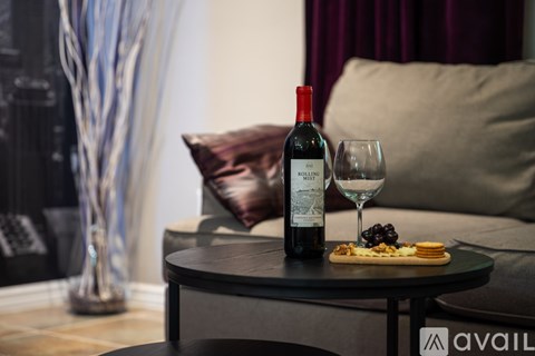 A bottle of wine and a glass on a table with a couch in the background.
