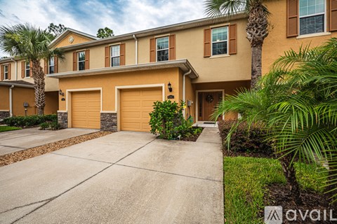 A house with a driveway and palm trees in front.