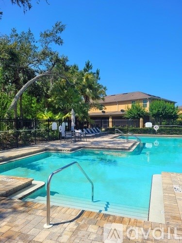 A pool surrounded by trees and a building in the background.