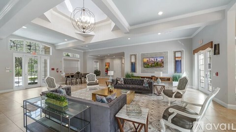 A spacious living room with a glass coffee table and a large chandelier.