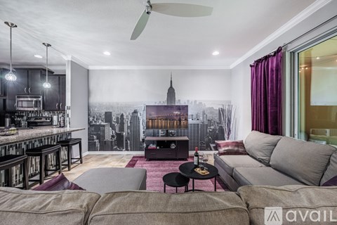 A living room with a large couch, a bar area, and a cityscape mural on the wall.