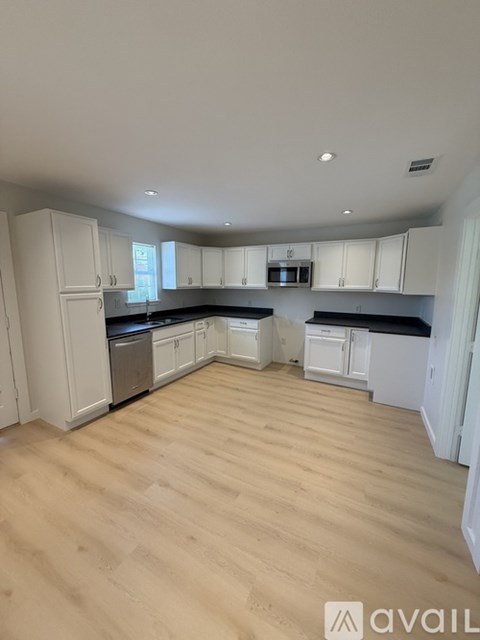 A kitchen with white cabinets and wooden flooring.
