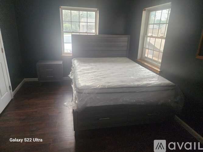 A bedroom with a bed, nightstand, and window.