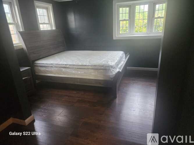 A bedroom with a bed, wooden floors, and a window.