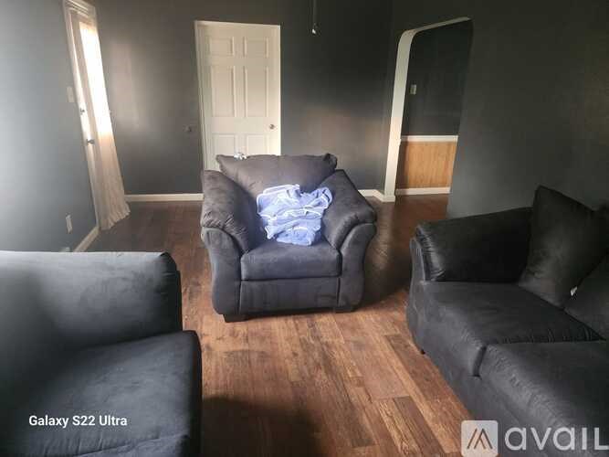 A living room with a black leather couch and a grey armchair.